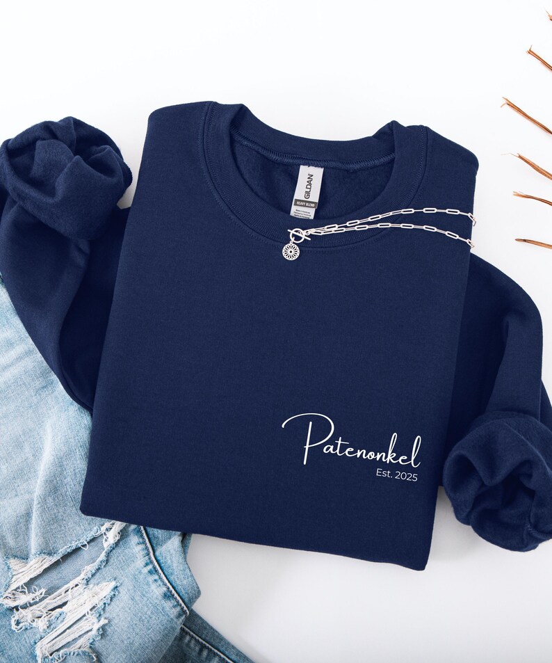 Puede incluir: Una sudadera azul marino de cuello redondo con texto bordado en blanco que dice Patenonkel Est. 2025 en la parte inferior derecha. La prenda tiene mangas largas con pu&ntilde;os acanalados y una etiqueta de la marca Gildan en el cuello.