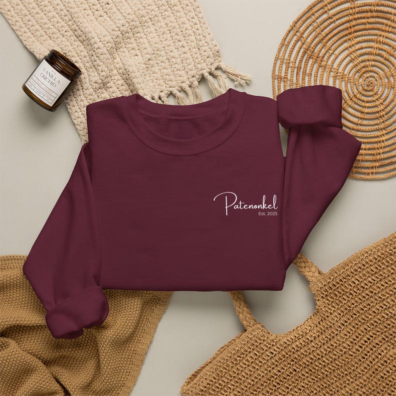 Puede incluir: Una sudadera de cuello redondo y manga larga en color burdeos intenso, con un texto bordado en blanco en el pecho izquierdo que dice Patenonkel Est. 2025 en una fuente cursiva. La prenda tiene un cuello redondo sencillo y pu&ntilde;os acanalados.