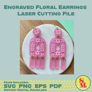 May include: Pink engraved floral earrings with a laser-cut design. The earrings feature a floral pattern and rectangular dangles. The image includes the text "ENGRAVED FLORAL EARRINGS LASER CUTTING FILE" and "SVG PNG EPS PDF INSTANT DIGITAL DOWNLOAD".