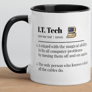 May include: White ceramic mug with a black interior and handle. The mug features the text "I.T. Tech" with a definition, including a computer graphic. The mug sits on a wooden surface.