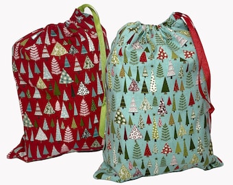 May include: Two Christmas gift bags with drawstring closures. One bag is red with a white and green Christmas tree pattern. The other bag is blue with a white and green Christmas tree pattern.