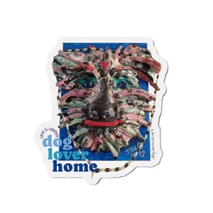 May include: A sticker featuring a colorful, textured dog face with blue eyes, a red heart, and a black nose. The text "dog lover home" is in blue and teal. The phrase "Love is Louder" is also included.
