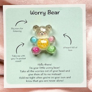 May include: A Worry Bear figurine on a card. The bear is made of clear, faceted material with colourful accents. The card has text that reads "Worry Bear" and includes the phrases "Big ears for listening," "A heart full of love," and "Take me with you; I'm pocket sized!"
