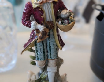 Antique German porcelain Sitzendorf young man carrying flower basket and a bird.