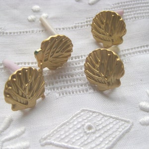 May include: Four gold seashell-shaped bottle stoppers with white stems.