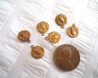May include: Six gold-toned metal charms featuring a beetle design. The charms are approximately the size of a US penny.