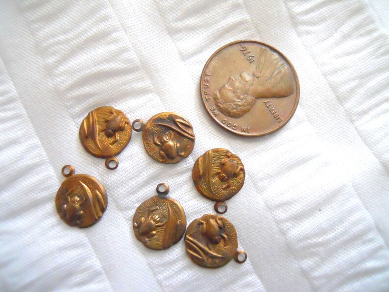 May include: Seven antique bronze charms with a frog design. Each charm has a loop for attaching to a necklace or bracelet.