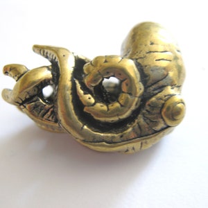 May include: A gold-colored metal sculpture of a curled octopus with detailed texture. The sculpture is a unique and intricate piece of art.