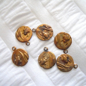 May include: Six gold-toned metal charms with a frog design. Each charm has a loop for attaching to a necklace or bracelet.