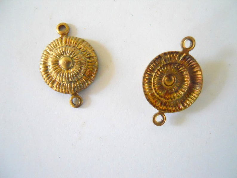 May include: Two gold-toned metal connector pieces with a circular design. Each piece has two loops for attaching to other jewellery or crafts.