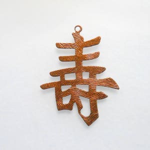 May include: A copper-colored metal charm in the shape of the Chinese character for "spring". The character is stylized with a textured surface.