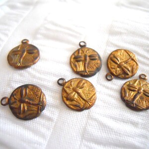 May include: Six gold-toned metal charms featuring a dragonfly design. Each charm has a loop for attaching to a necklace, bracelet, or other jewelry.