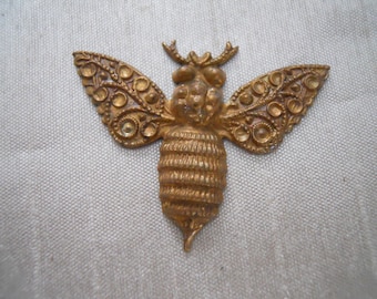 May include: A gold-toned metal bee charm with intricate details. The bee has a detailed body and wings with a raised design.