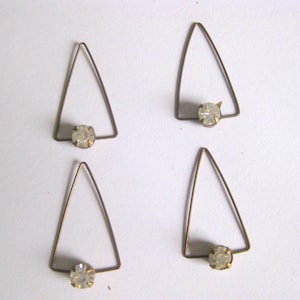 May include: Four vintage triangle-shaped earrings. Each earring features a clear, round gemstone set at the base of a thin, gold-toned metal triangle. The earrings are displayed against a plain white background.