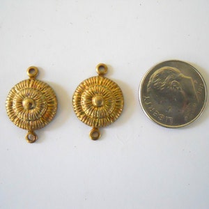 May include: Two gold-toned metal connector pieces with a circular design. Each piece has two loops for attaching to jewellery or other crafts.
