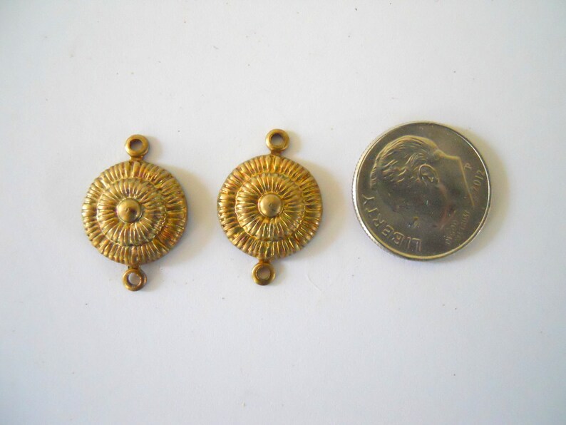 May include: Two gold-toned metal connector pieces with a circular design. Each piece has two loops for attaching to jewellery or other crafts.