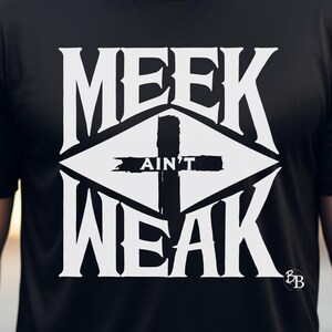 Może przedstawiać: Czarny T-shirt z białym nadrukiem graficznym, na którym widnieje napis "MEEK AIN'T WEAK" z krzyżem w środku. Grafika ma kształt rombu.