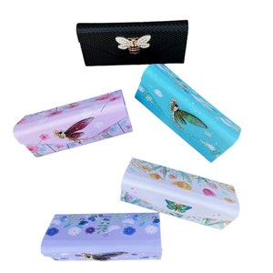 Peut inclure: Cinq étuis à lunettes différents avec des motifs floraux et d'insectes. Les étuis sont faits d'un matériau doux et ont un rabat qui se ferme à l'aide d'un fermoir magnétique. Les étuis sont disponibles dans une variété de couleurs, notamment le noir, le rose, le bleu, le blanc et le violet.