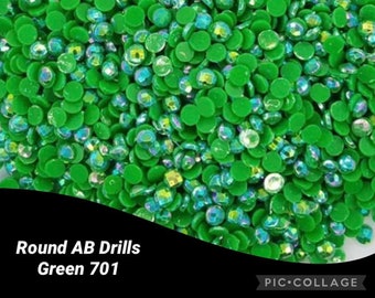 Puede incluir: Primer plano de un montón de diamantes de imitación redondos AB verdes, con un efecto iridiscente. La imagen incluye el texto "Round AB Drills Green 701" en blanco sobre un fondo negro.