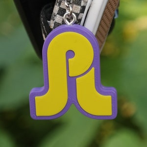 May include: A purple keychain with a yellow letter P charm. The charm is shaped like a stylized letter P with a rounded, retro design.