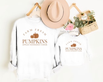 May include: Two white long-sleeved shirts with the text "FARM FRESH PUMPKINS APPLES HAYRIDES CIDER" and a graphic of three pumpkins.