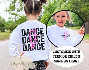Könnte beinhalten: Weißer Pullover mit dem Wort "Dance", das viermal mit einem rosa Blitz wiederholt wird. Auf der Rückseite des Pullovers steht "TAYLOR" mit einem rosa Blitz.  Individualisieren Sie mit dem Namen des Teams oder des Kindes auf der Vorderseite.