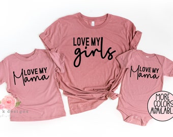 Könnte beinhalten: Drei rosa T-Shirts mit schwarzem Text. Das größte Shirt sagt "Love My Girls". Das mittlere Shirt sagt "Love My Mama". Das kleinste Shirt sagt "Love My Mama".