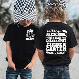 May include: Two children wearing black t-shirts with white text. The front shirt says "2024 MASON" with a smiley face wearing a graduation cap. The back shirt says "so long PRESCHOOL it's been fun LOOK OUT KINDERGARTEN here i come!"