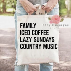 May include: A white canvas tote bag with black text that reads "Family, Iced Coffee, Lazy Sundays, Country Music".