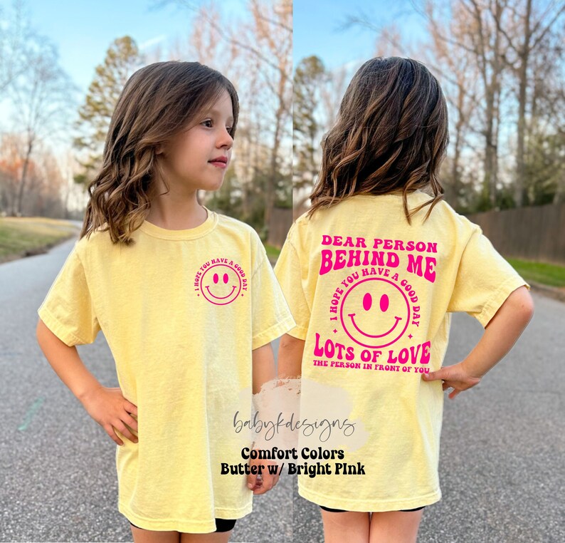 May include: Yellow t-shirt with a pink smiley face on the front and the text "Dear Person Behind Me I Hope You Have A Good Day Lots Of Love The Person In Front Of You" on the back.