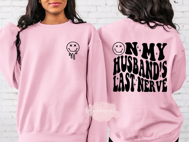 May include: Pink sweatshirt with a dripping smiley face on the front and the text "On my husband's last nerve" on the back.