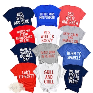 Op de afbeelding: Een set van 12 T-shirts met rode, witte en blauwe tekst op verschillende gekleurde shirts. De shirts bevatten patriottische en humoristische spreuken zoals "Red, Wine, and Blue", "Little Miss Independent", "Red, White, & Boozy", "Keep Calm and Sparkle On", "Born to Sparkle", "We the People Like to Party", "Grill and Chill", "Lady Lit-Berty", "Have a Yankee Doodle Day", "I'm Not Drunk I'm Patriotic", "United We Stand Intoxicated We Fall" en "Red, White, and Brew".