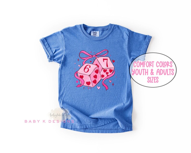 May include: Blue t-shirt featuring a graphic of two dice with the numbers 6 and 7, decorated with pink hearts and a pink ribbon. The text "Comfort Colors Youth & Adults Sizes" is in a white oval.