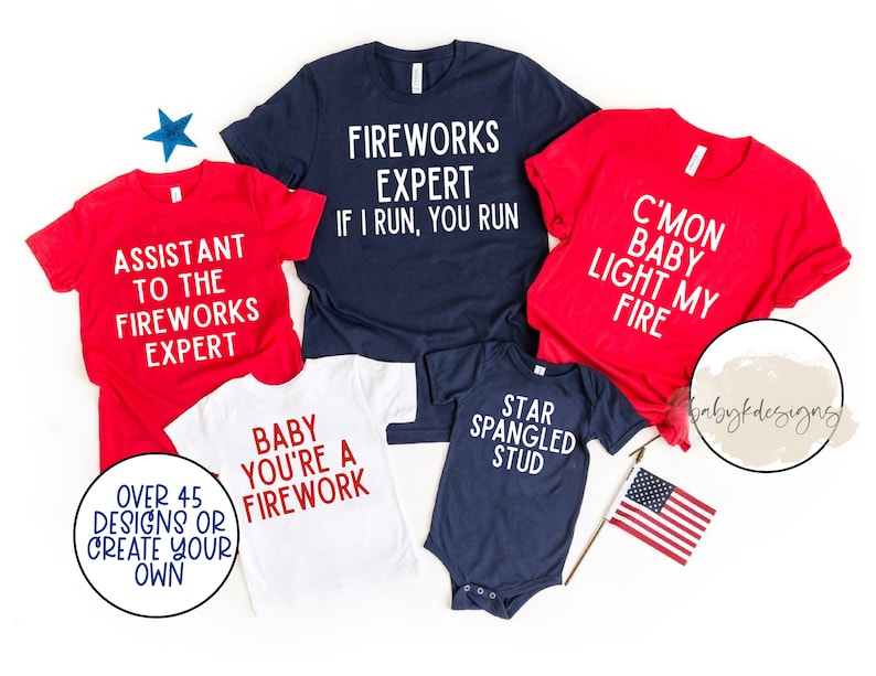 Op de afbeelding: Vijf rood, wit en blauwe shirts met tekst die luidt "Assistant to the Fireworks Expert", "Fireworks Expert If I Run, You Run", "C'mon Baby Light My Fire", "Baby You're a Firework", en "Star Spangled Stud".