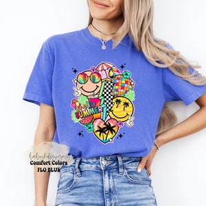 May include: A blue Comfort Colors t-shirt with a vibrant graphic of smiley faces, a disco ball, and the words "Hello Summer!". The design includes a watermelon slice, peace signs, and a heart with palm trees. The shirt is a Flo Blue colour.