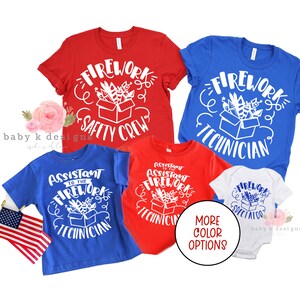 May include: Several red, blue, and white t-shirts and a baby onesie with firework-themed graphics. The shirts display phrases such as "Firework Safety Crew" and "Assistant to the Firework Technician". An American flag is also visible.