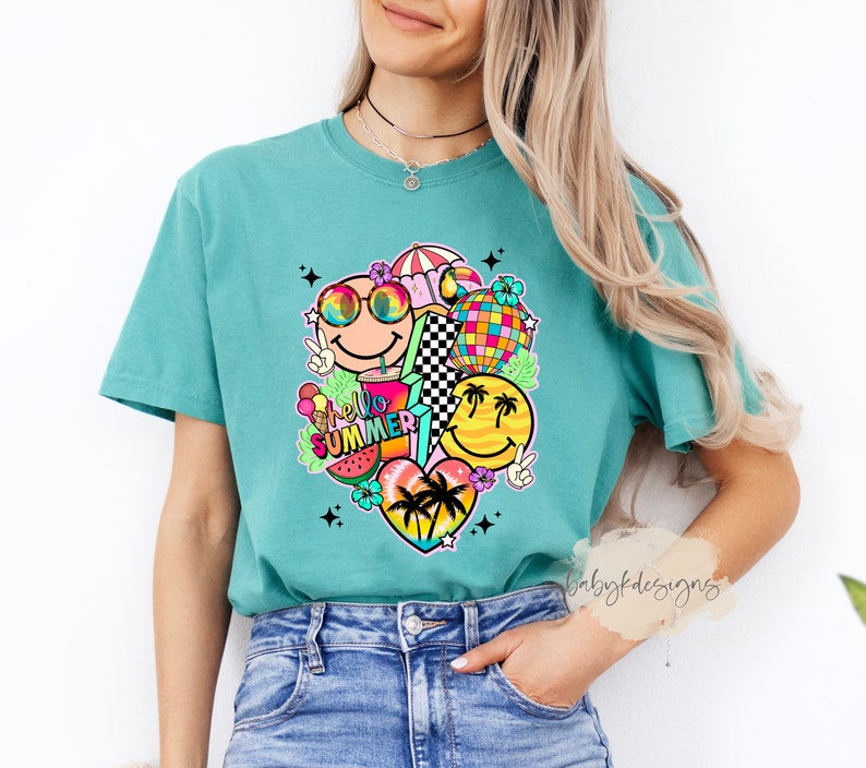May include: Teal t-shirt with a vibrant graphic of smiley faces, sunglasses, a disco ball, and the words "Hello Summer." The design incorporates a watermelon slice, ice cream, and palm trees. The shirt is made of a soft material.