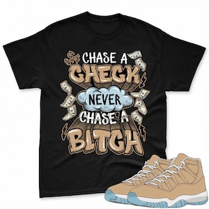 May include: Black t-shirt with the text "CHASE A CHECK NEVER CHASE A BITCH" in a brown and white design. The shirt features dollar signs and money graphics. A pair of tan and blue sneakers are in the foreground.