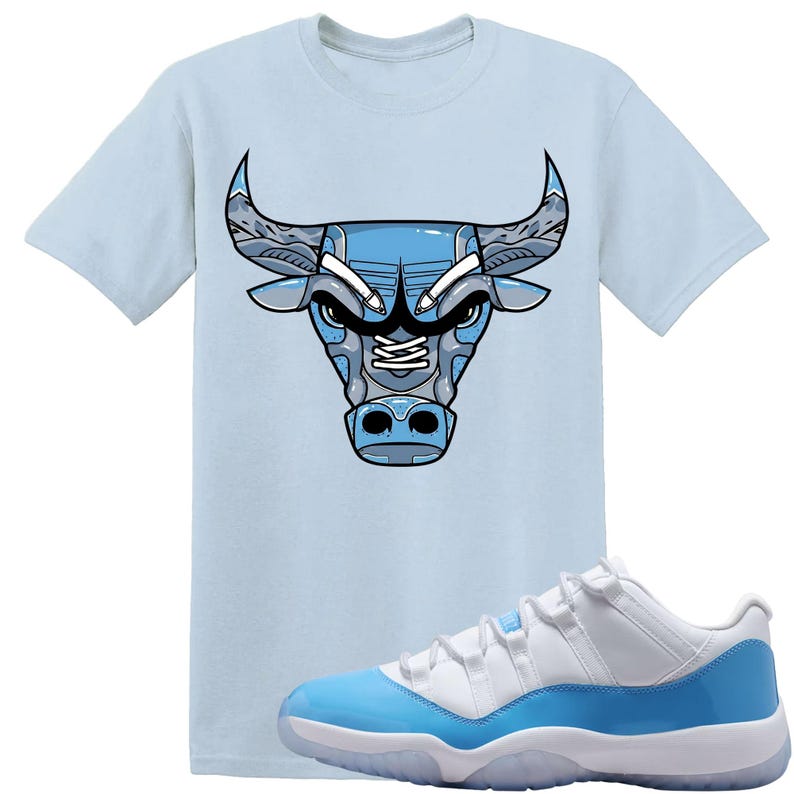 May include: A pale blue t-shirt with a blue and grey bull head design. The image also shows white and light blue trainers with a translucent sole. The shirt and trainers share a similar colour palette.