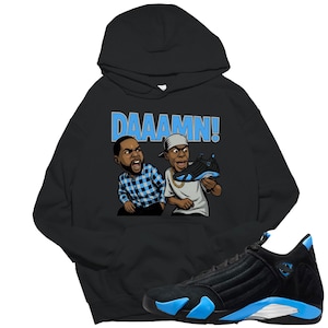 May include: Black hoodie with a graphic of two cartoon figures and the word "DAAAMN!" in light blue. The hoodie is paired with a black and blue sneaker.