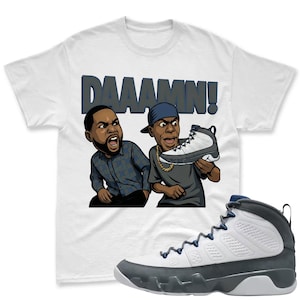 May include: White t-shirt with the word "DAAAMN!" above a cartoon illustration of two men. One man is holding a white, gray, and blue sneaker. A matching sneaker is displayed below the shirt.