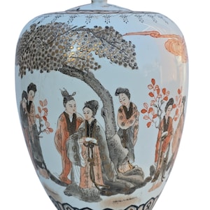 May include: A white ceramic ginger jar with a lid, featuring a hand-painted scene of figures under a tree. The jar has a gold finial and a decorative black and gold border at the base. The artwork includes orange and gold accents.