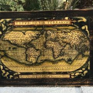 May include: A black wooden frame with a vintage world map print. The map is in a yellow, brown, and blue color scheme and features the text "Typus Orbis Terrarum".