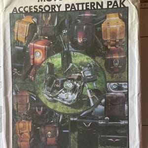 May include: A white paper envelope labeled MOTORCYCLE ACCESSORY PATTERN PAK featuring various leather saddlebags and tool pouches with embossed designs, including skulls and wings, surrounding a central image of a motorcycle.