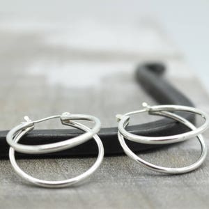 May include: A pair of silver hoop earrings with a double hoop design. The earrings are simple and elegant.
