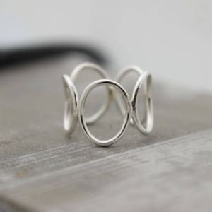 May include: A silver ring with a unique design featuring multiple interconnected circles.