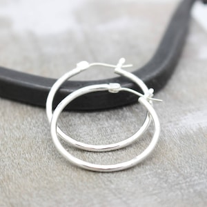 May include: A pair of silver hoop earrings. The earrings are simple and elegant, with a smooth, polished finish.