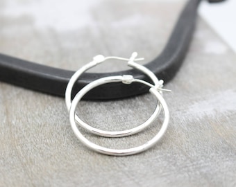 May include: A pair of silver hoop earrings. The earrings are simple and elegant, with a smooth, polished finish.