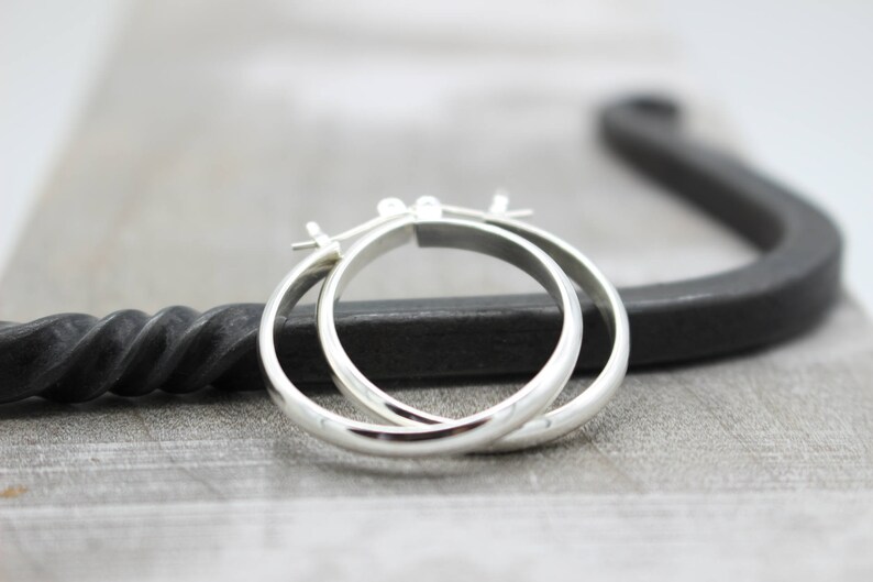 May include: A pair of silver hoop earrings. The earrings are simple and elegant, with a smooth, polished finish.