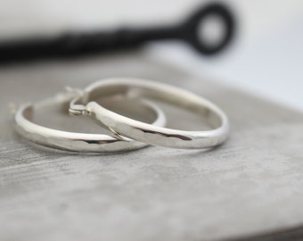 May include: A pair of silver hoop earrings with a hammered texture.